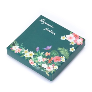 Macro view of dark green square gift box featuring tropical floral and butterfly patterns