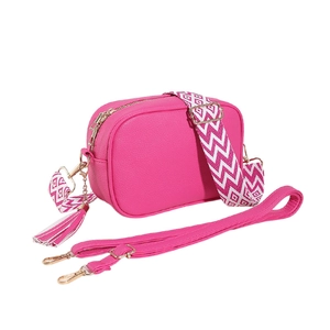 Fuchsia crossbody bag with wide woven strap, tassel, and smooth faux leather texture