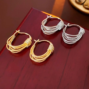 Détail de créoles multicouches plaquées or 14K avec zircons et design torsadé chic