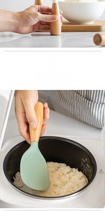 Detail of light green silicone rice paddle with non-stick texture and ergonomic wooden handle
