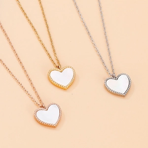Detaillierte Ansicht von drei Herzanhängern in Gold, Silber und Roségold mit Perlenrand