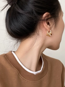 Détail des boucles d'oreilles en or 18 carats avec œil de tigre et perles portées par modèle