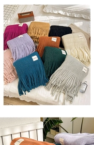 Close-up of knit texture with 'HAND MADE' patch and colorful long fringe tassels