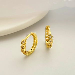 Detailed macro view of gold heart hoop earrings with micro-inlaid clear zircon stones