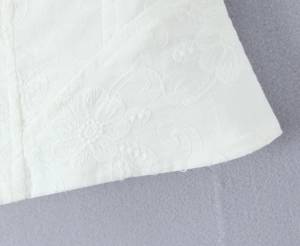 Close-up of intricate white floral embroidery on premium cotton blend camisole fabric