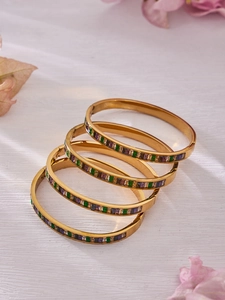 Stack of gold stainless steel bangles with purple green and white rectangle zircon stones