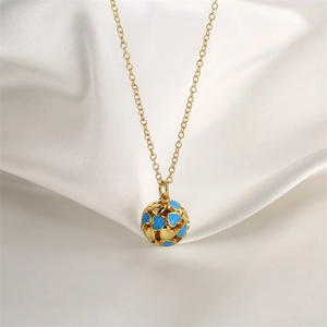 Macro shot of gold necklace with blue enamel heart sphere pendant on white silk
