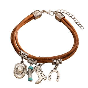 Detail of multi-layer brown leather bracelet with silver Western cowgirl charms and lucky charms