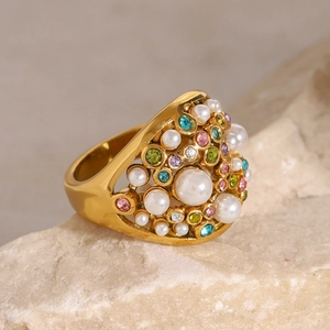 Detailed close-up of a gold-toned ring with multi-color crystals and white pearls on stone