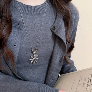 Detailed view of long silver chain with layered flower pendants and tiger eye beads