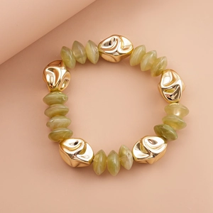 Detail of olive green resin beads and irregular gold metal accents on a beaded bracelet