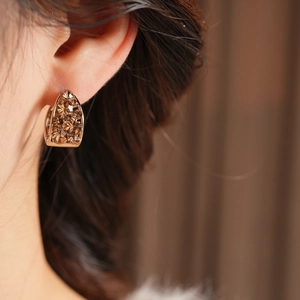 Gros plan d'une femme portant des boucles d'oreilles créoles dorées et cristaux ambre