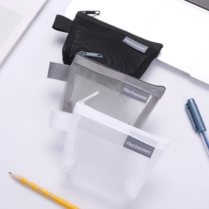 Three triangular nylon mesh pouches in black, grey, and white on a desk with office supplies