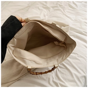 Interior view of large beige tote bag featuring a retro bamboo handle and zipper pocket