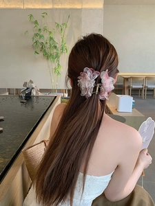 Vista posteriore di una modella con molletta per capelli a fiore in mesh rosa in un giardino