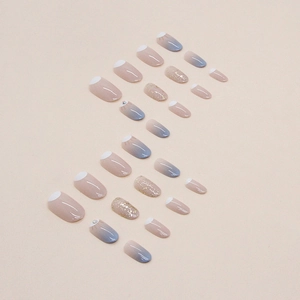 Blue gradient oval press-on nails with glitter and rhinestones on a beige background