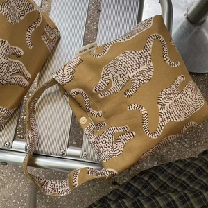 Détail du sac cabas en toile à imprimé léopard avec fermeture aimantée et étiquette tissée