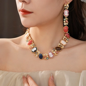 Close-up of vintage gold necklace and earrings set with relief portraits and crystals