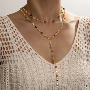 Detail of layered gold Y-necklace featuring colorful stones on a female model