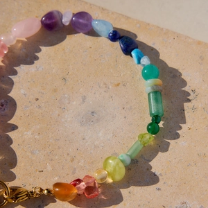 Macro view of multi-colored natural stone beads with gold lobster clasp and stone texture