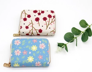 Detailed view of floral Saffiano leather card holders with secure golden metal zippers