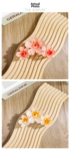 Detail von bunten Plumeria-Haarklammern aus Harz in Rosa und Weiß auf Holzdisplay