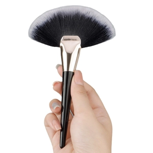 Large fan-shaped makeup brush with black-white gradient bristles and rose gold ferrule
