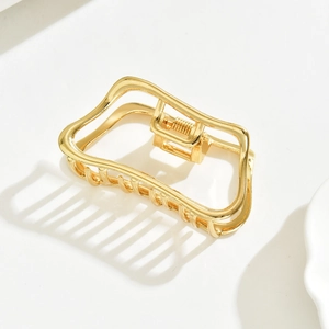 Close-up of elegant gold metal hair claw clip with a hollow rectangular design