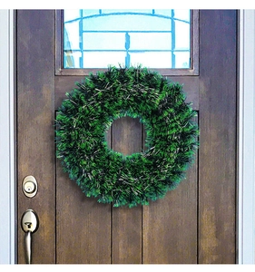 Festive green and silver tinsel Christmas wreath hanging on a wooden front door.