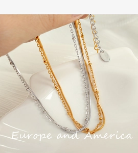 Close-up of double-layered gold and silver necklaces with snake chain and beads