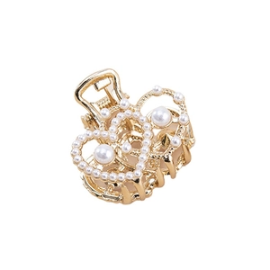 Pince à cheveux double cœur doré ornée de perles et strass sur fond blanc épuré