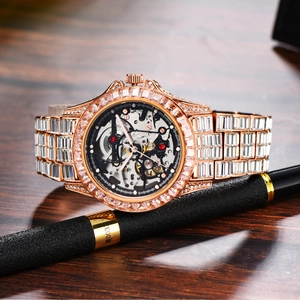 Macro shot of rose gold skeleton mechanical watch with baguette crystals on wood