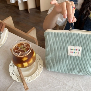Detail view of mint green corduroy toiletry bag with embroidered patch and ring zipper