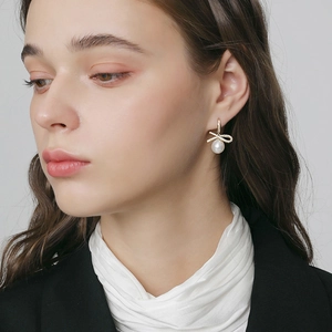 Detailed close-up of bow knot earrings with white pearls and sparkling cubic zirconia