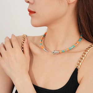 Detail of snake collar necklace with orange and green beads and a golden metal head