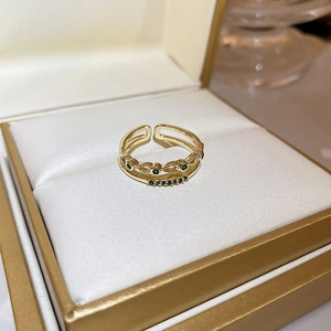 Detailed close-up of a gold double-layer open ring with green gems and micro-pave crystals