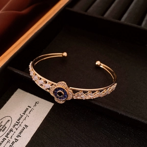 Close-up of golden flower bracelet with blue zircon petals on black velvet padding
