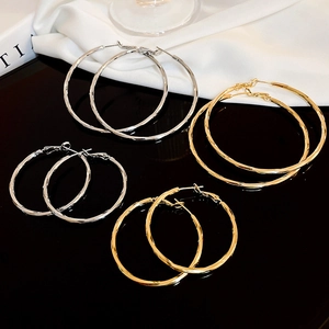 Detail of faceted gold and silver hoop earrings on elegant black and white background