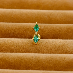 Detail of gold screw-back cartilage earring with marquise green zircon in a velvet box