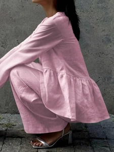 Pink linen style long sleeve top with ruffle hem and matching pants set on a concrete wall