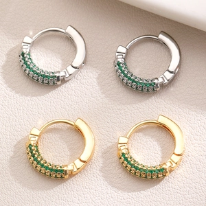 Close-up of gold and silver hoop earrings featuring pavé green zircon stones