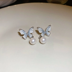 Macro view of silver butterfly earrings with crushed ice texture and pearl drops