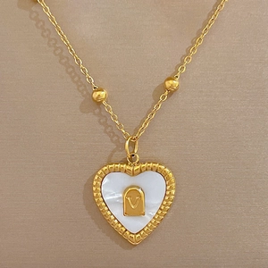 Detailed close-up of a gold heart pendant with shell inlay and V-shaped metal accent
