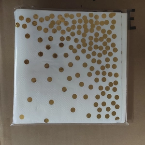 Detail of disposable white napkins with gold polka dots in plastic packaging