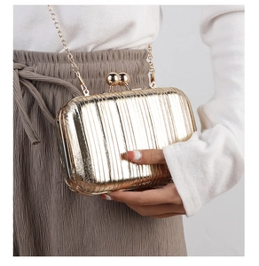 Detailed macro view of gold evening clutch bag with vertical pleated texture and ball clasp