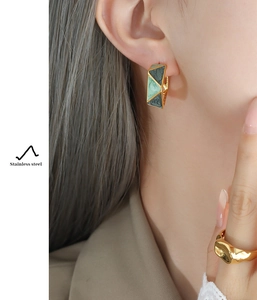 Detail of gold-plated stainless steel geometric earrings with green marble inlay on ear
