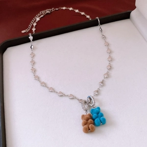 Détail de la chaîne argentée en cœur avec pendentifs d'oursons floqués marron et bleu