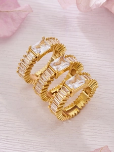 Detailed macro view of 18k gold plated rings with emerald cut zircon stones and pavé setting