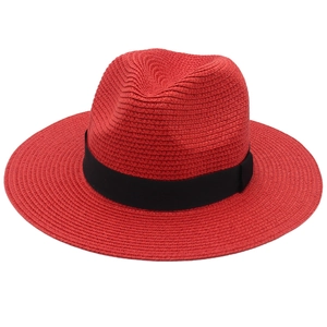 Detail of red panama straw hat with a black ribbon band and fine woven texture
