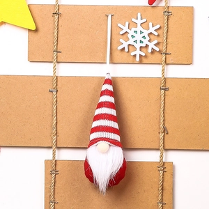 Detailed view of handmade Christmas gnome ornament with red knitted hat on wooden stand
